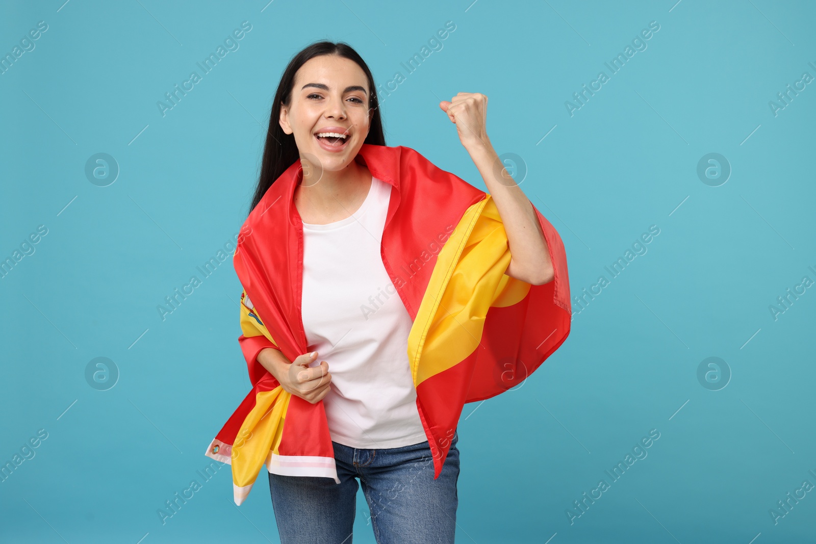 Photo of Happy young woman with flag of Spain on light blue background