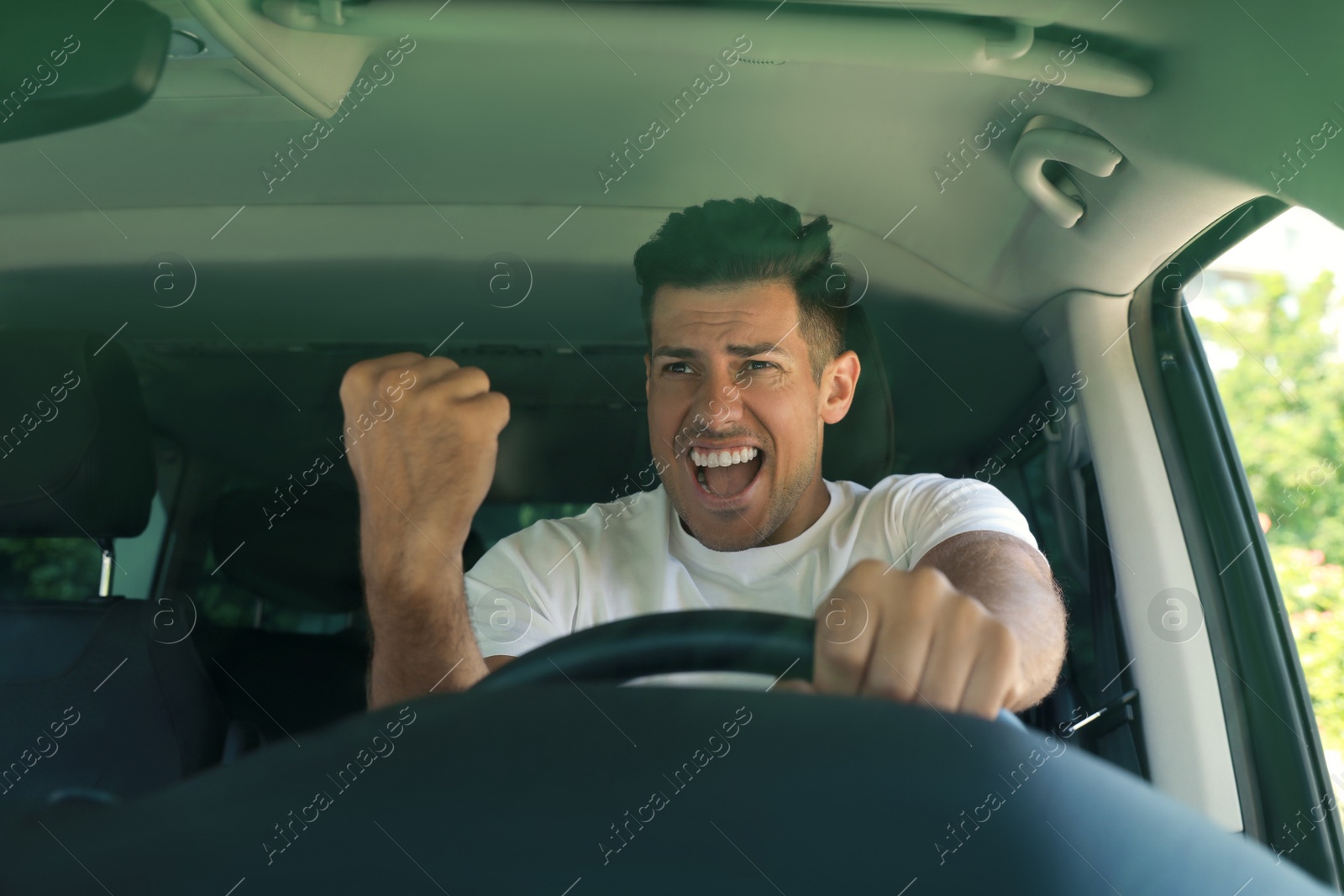 Photo of Stressed angry man in driver's seat of modern car, view through windshield