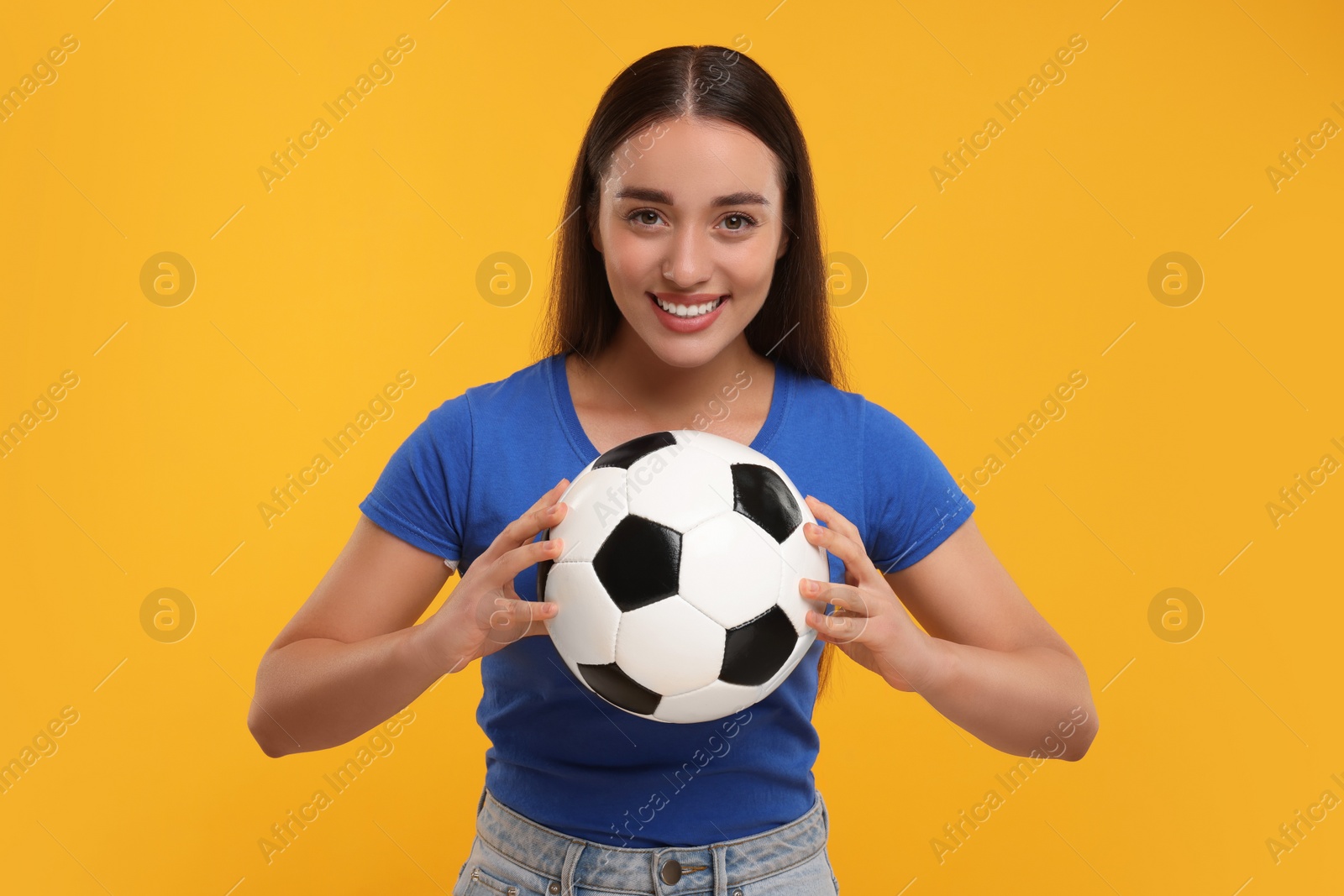 Photo of Happy fan holding soccer ball on yellow background