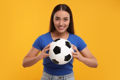 Happy fan holding soccer ball on yellow background