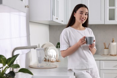 Photo of Happy woman with cup of drink in kitchen. Lazy morning