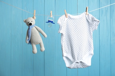 Photo of Baby accessories on laundry line against color wooden background