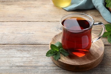 Photo of Cup of hot aromatic tea with mint on wooden table. Space for text