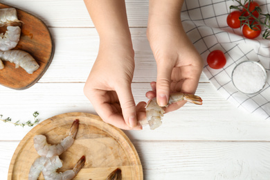 Photo of Woman peeling fresh shrimp at table, top view