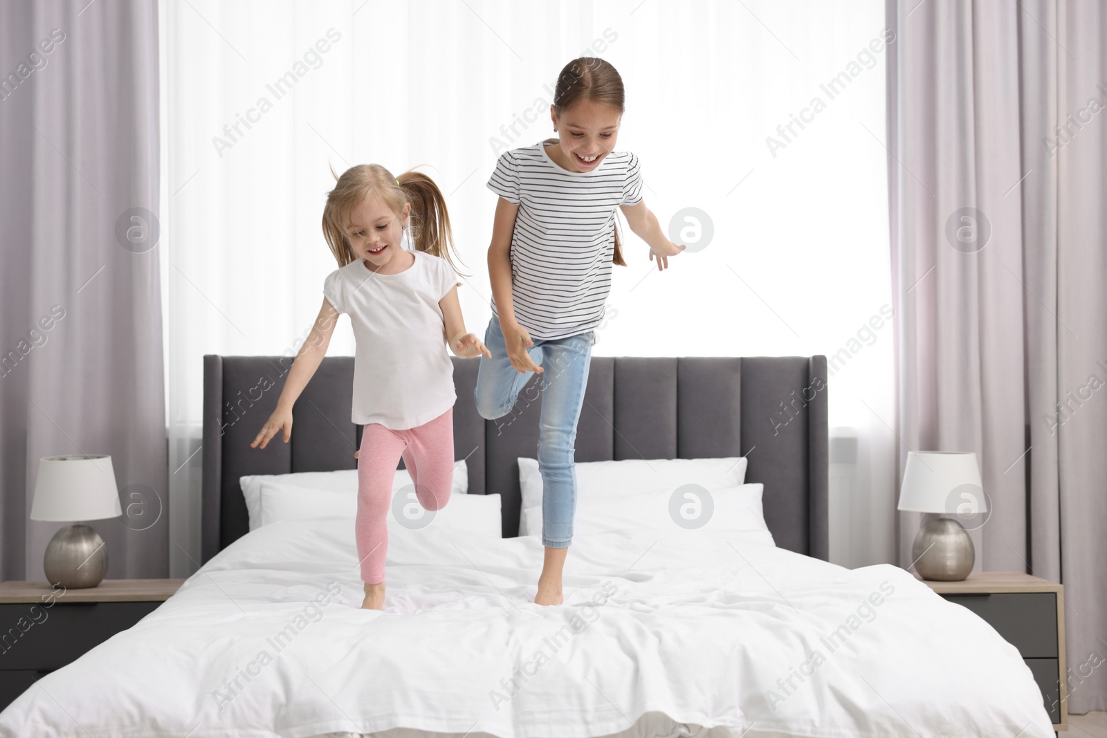 Photo of Cute little sisters having fun together on bed at home