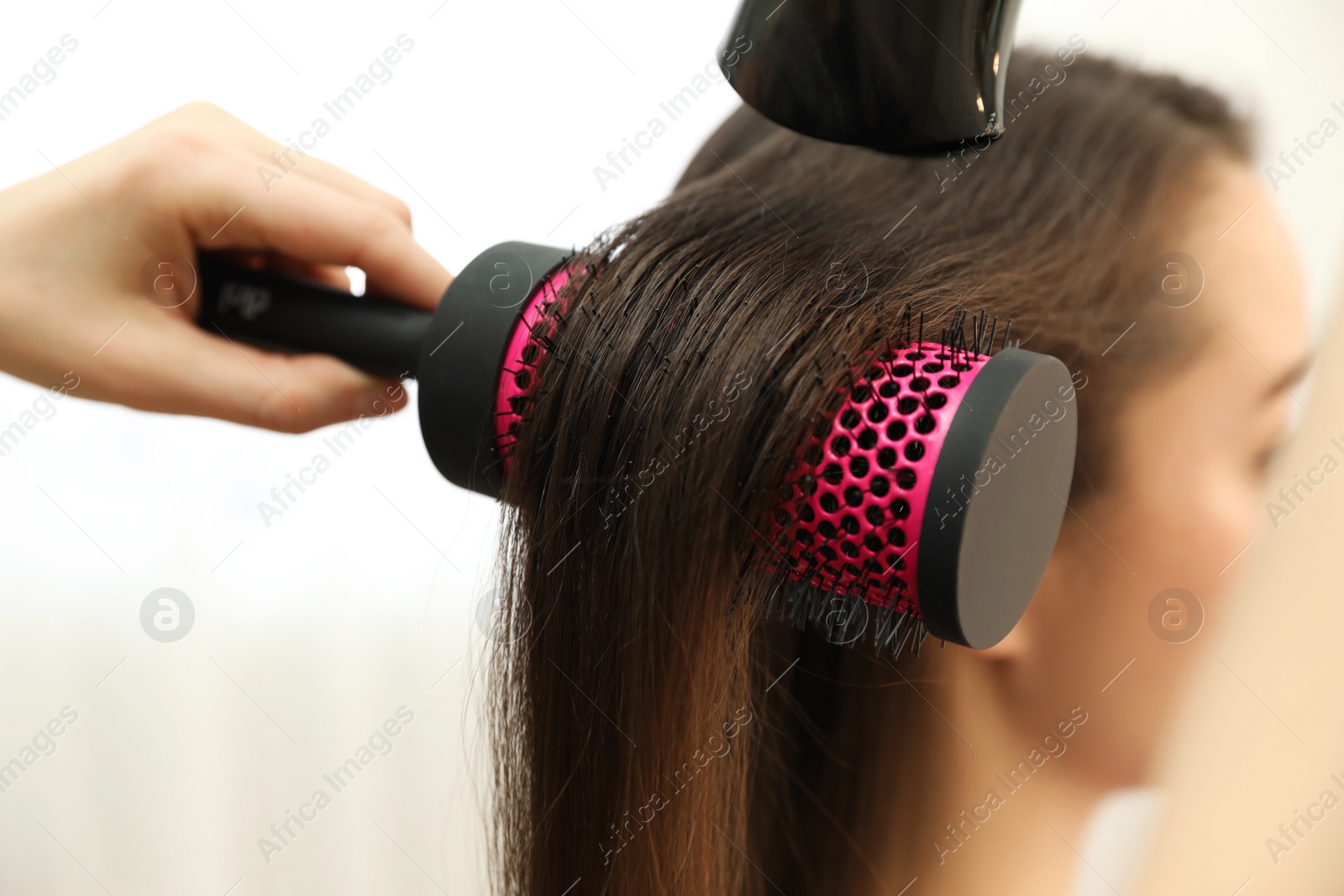 Photo of Stylist drying client's hair in beauty salon, closeup