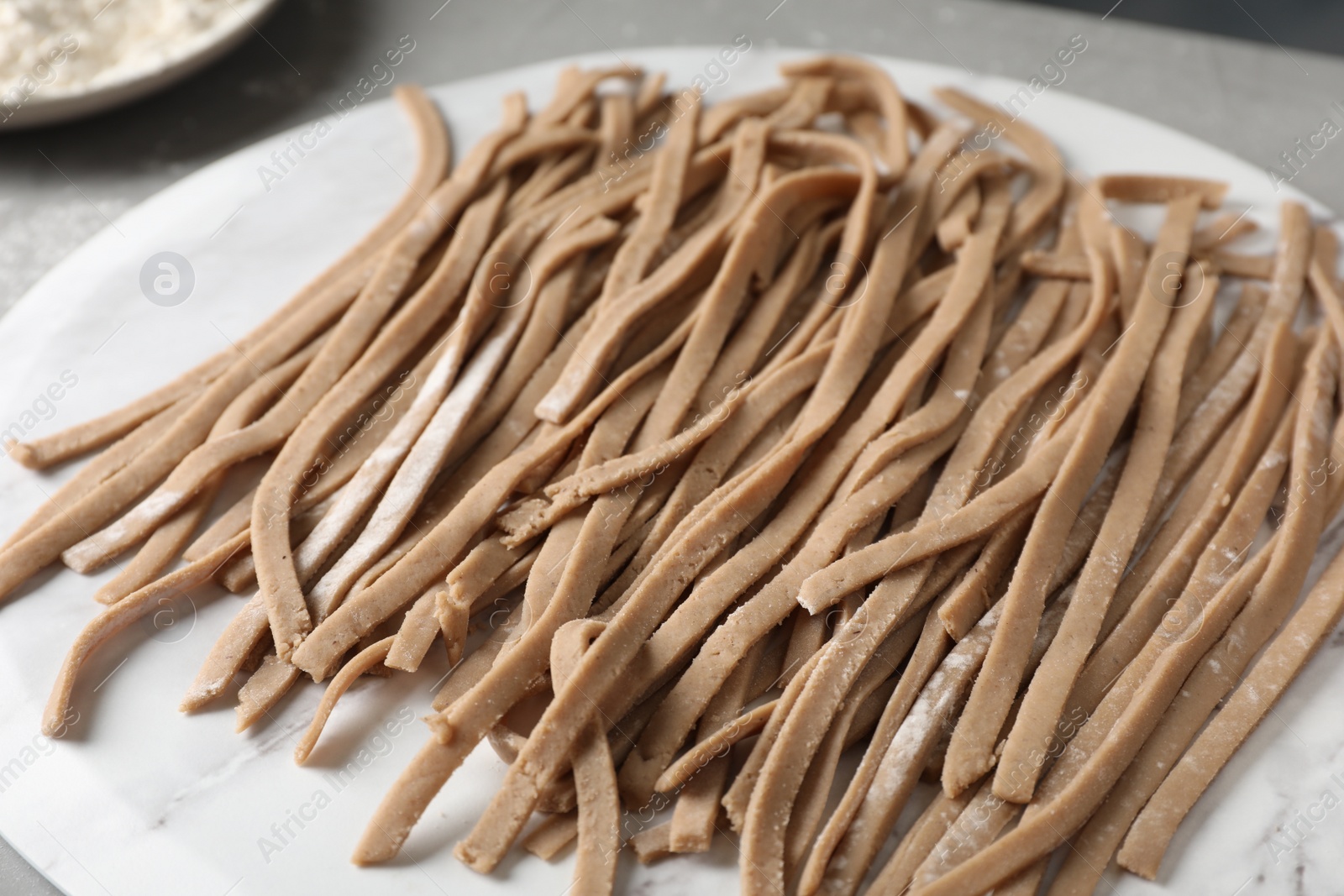 Photo of Uncooked homemade soba (buckwheat noodles) on marble board, closeup