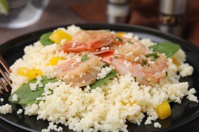 Photo of Tasty couscous with shrimps, bell pepper and basil on table, closeup