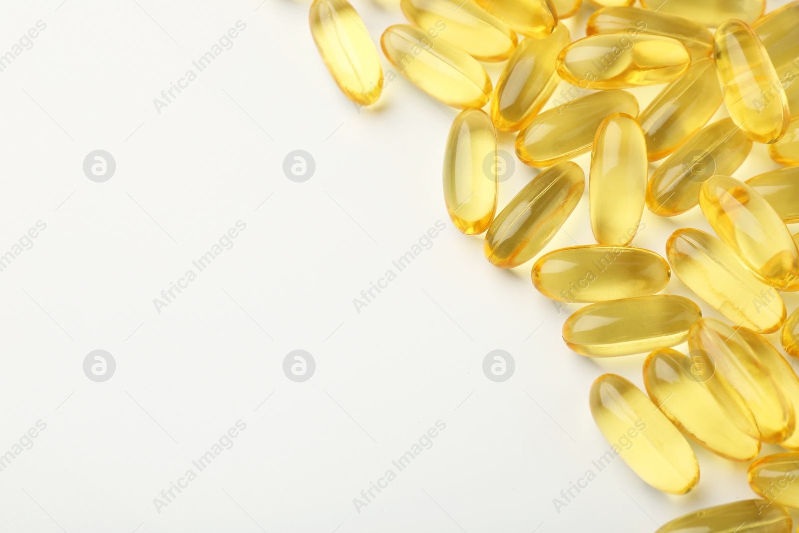 Photo of Yellow vitamin capsules on white background, top view. Space for text