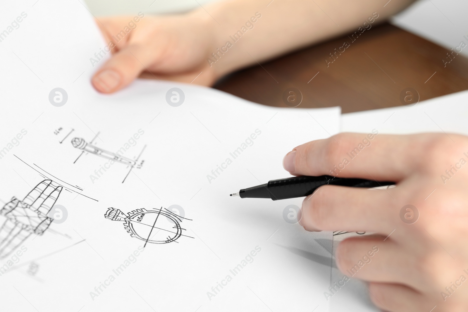 Photo of Jeweler with sketches of elegant jewelry at table, closeup