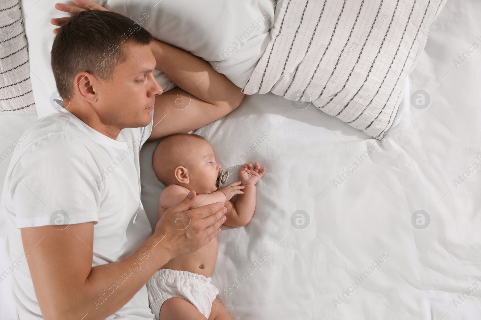 Photo of Father and baby sleeping on bed together, top view. Space for text