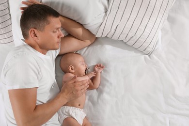 Photo of Father and baby sleeping on bed together, top view. Space for text