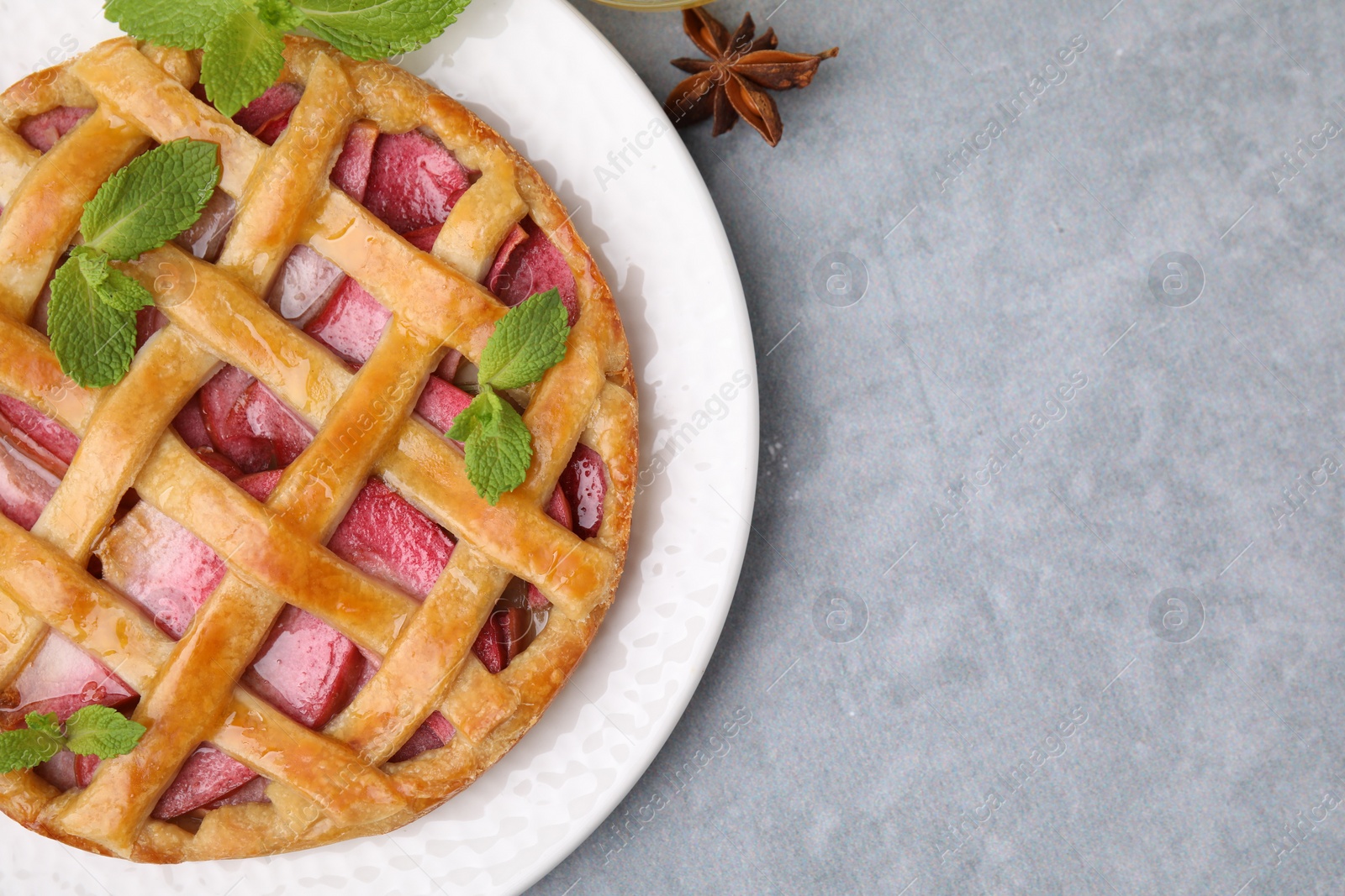 Photo of Delicious apple pie with mint and anise on grey table, top view. Space for text