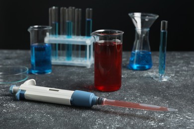 Laboratory analysis. Micropipette and different glassware on grey table