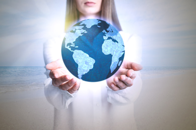 Image of Woman holding Earth at beach, closeup view