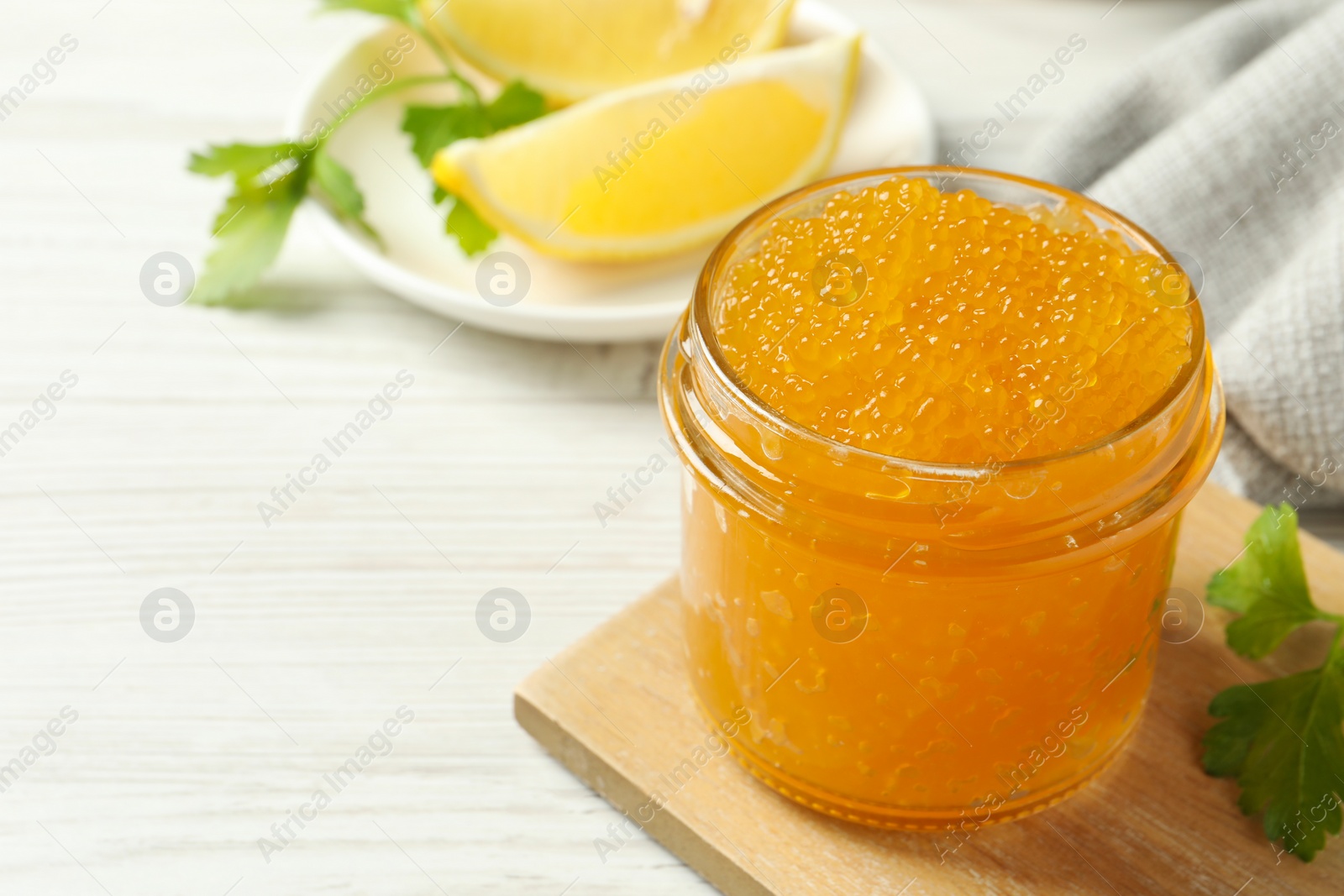 Photo of Fresh pike caviar in glass jar and parsley on white wooden table, closeup. Space for text