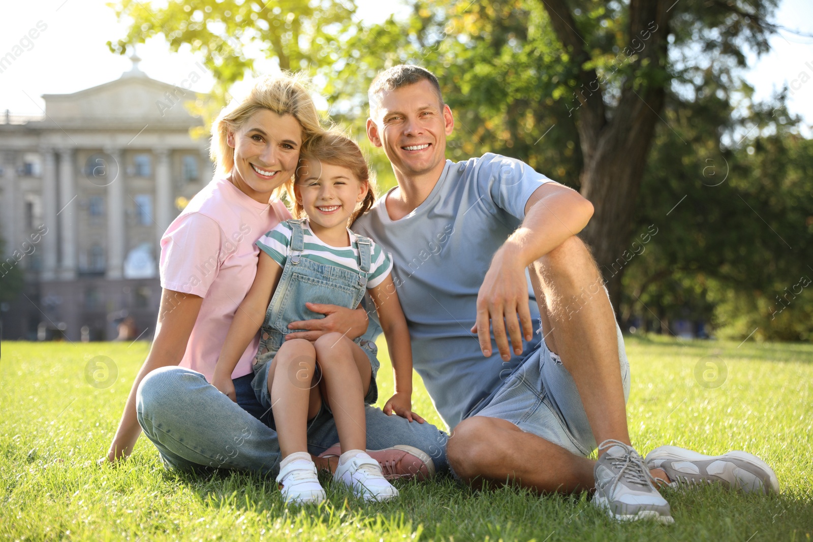 Photo of Happy parents with their child having fun on green grass. Spending time in nature