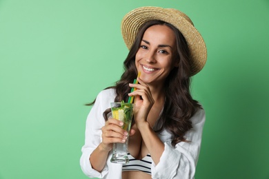 Young woman with refreshing drink on green background