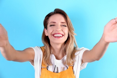 Photo of Beautiful laughing woman taking selfie on color background