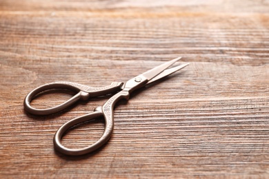 Photo of Vintage scissors on wooden background. Tailoring equipment