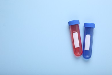 Photo of Test tubes with colorful liquids on light blue background, flat lay and space for text. Kids chemical experiment set