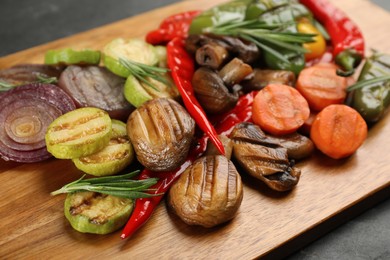 Photo of Delicious grilled vegetables with rosemary on wooden board, closeup