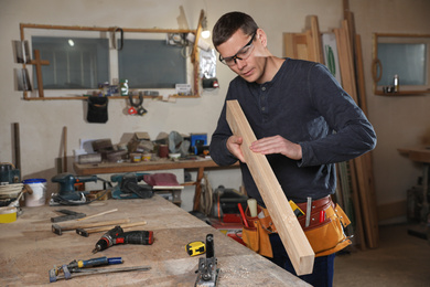 Professional carpenter working with wooden plank in workshop