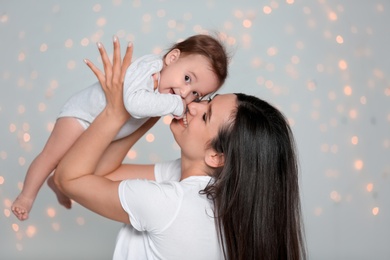 Young mother with her cute little baby against defocused lights