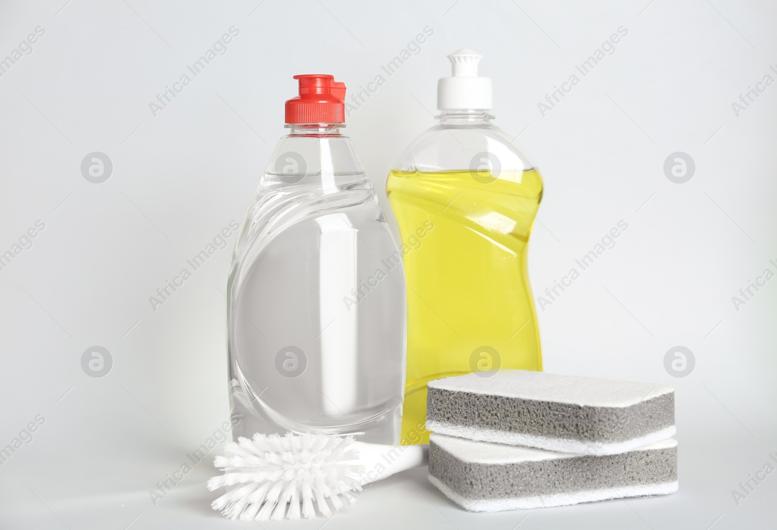 Photo of Detergents, brush and sponges on light background. Clean dishes