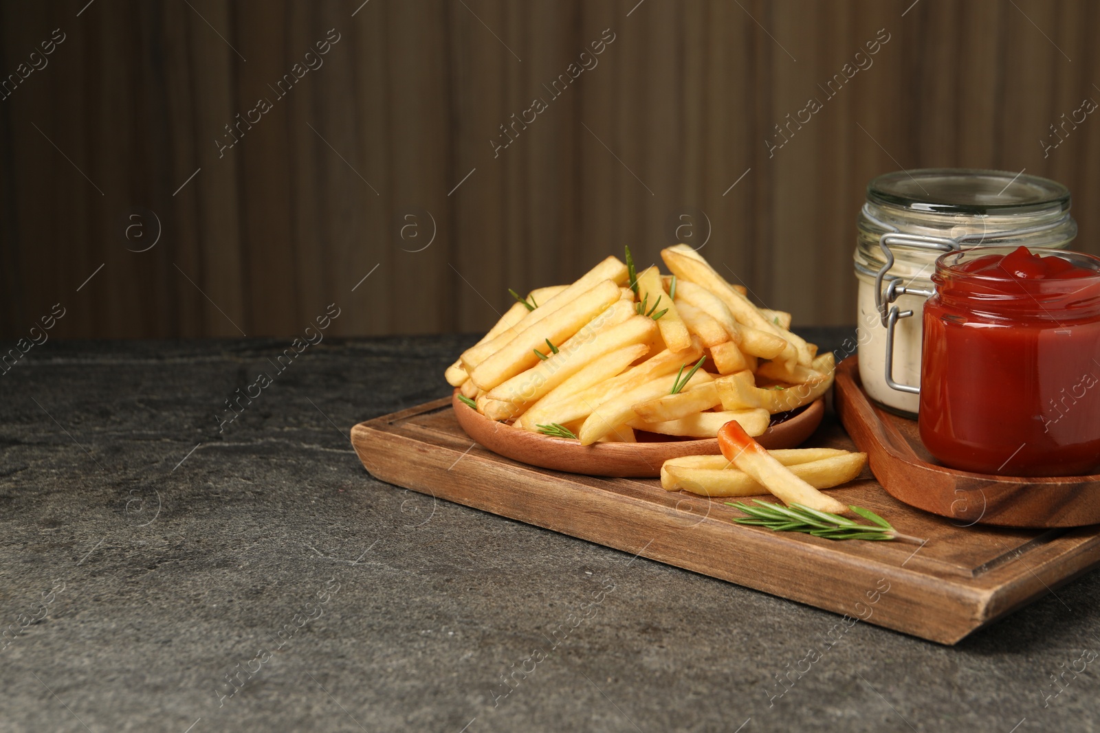 Photo of Delicious french fries served with sauces on grey textured table. Space for text