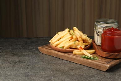 Photo of Delicious french fries served with sauces on grey textured table. Space for text