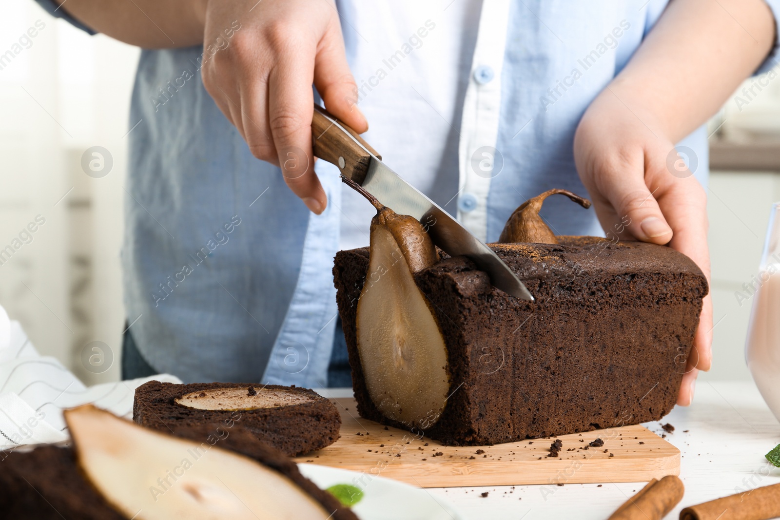 Photo of Woman cutting tasty pear bread at table, closeup. Homemade cake