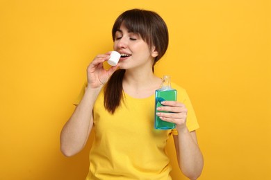 Photo of Young woman using mouthwash on yellow background