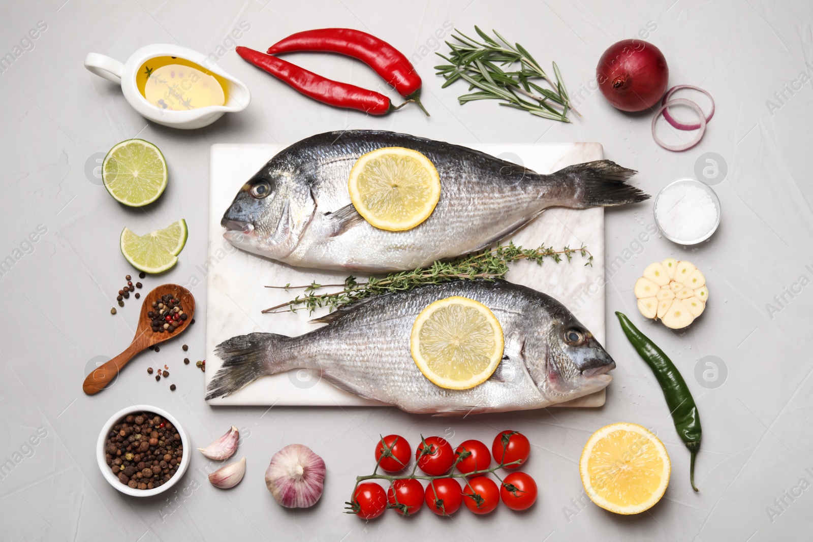 Photo of Flat lay composition with fresh raw dorado fish and ingredients on light grey table