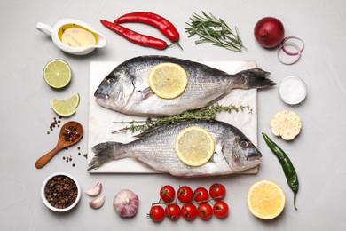 Flat lay composition with fresh raw dorado fish and ingredients on light grey table