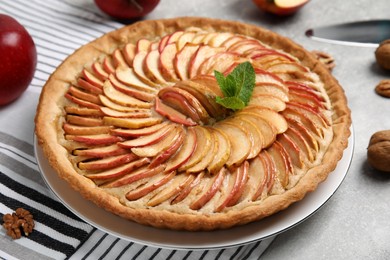 Photo of Delicious homemade apple tart with mint on grey table