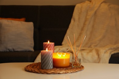 Photo of Beautiful candles and reed air freshener on white table indoors. Cosy atmosphere