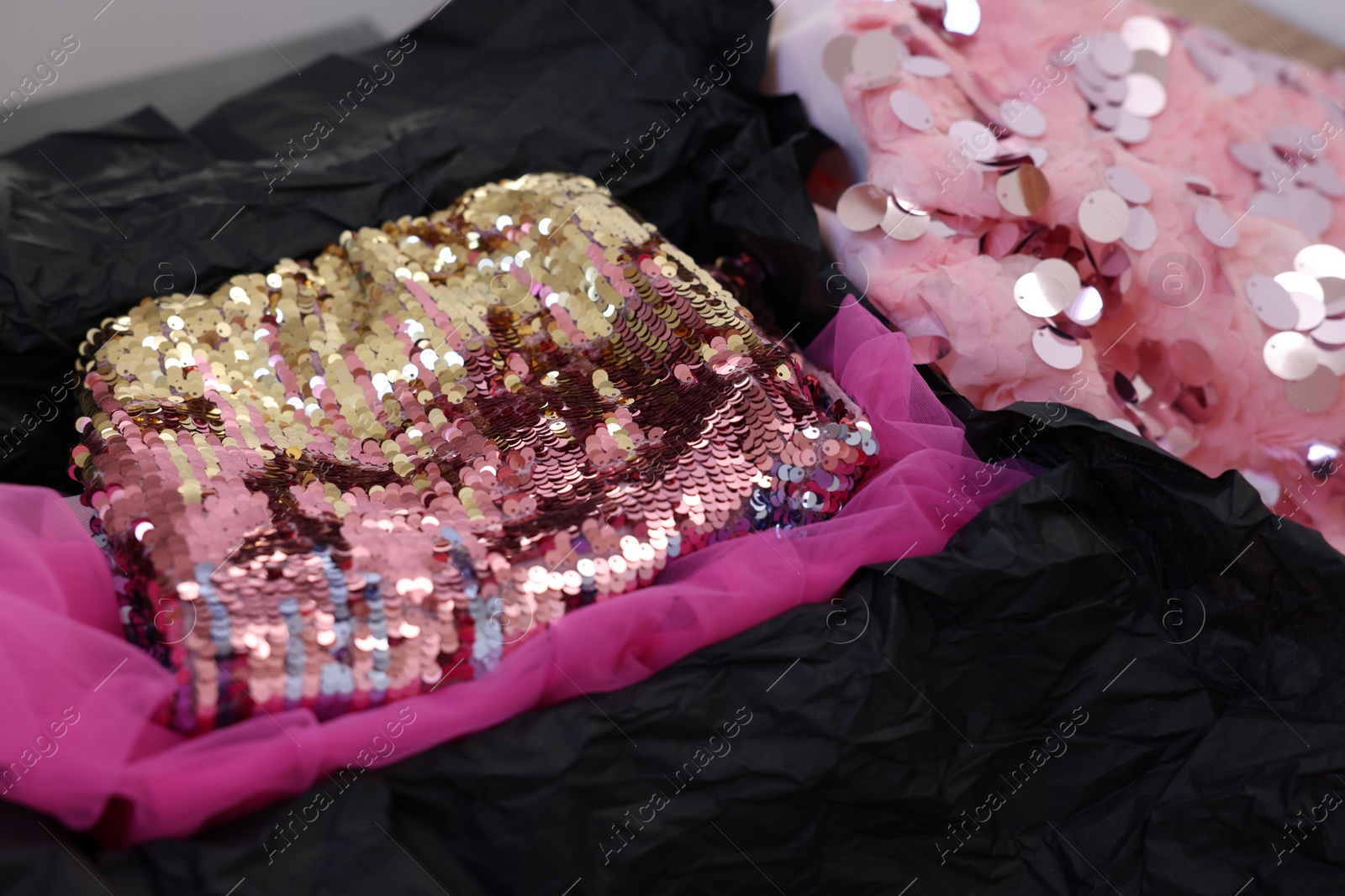 Photo of Stylish pink carnival costume with sequins in black box, closeup