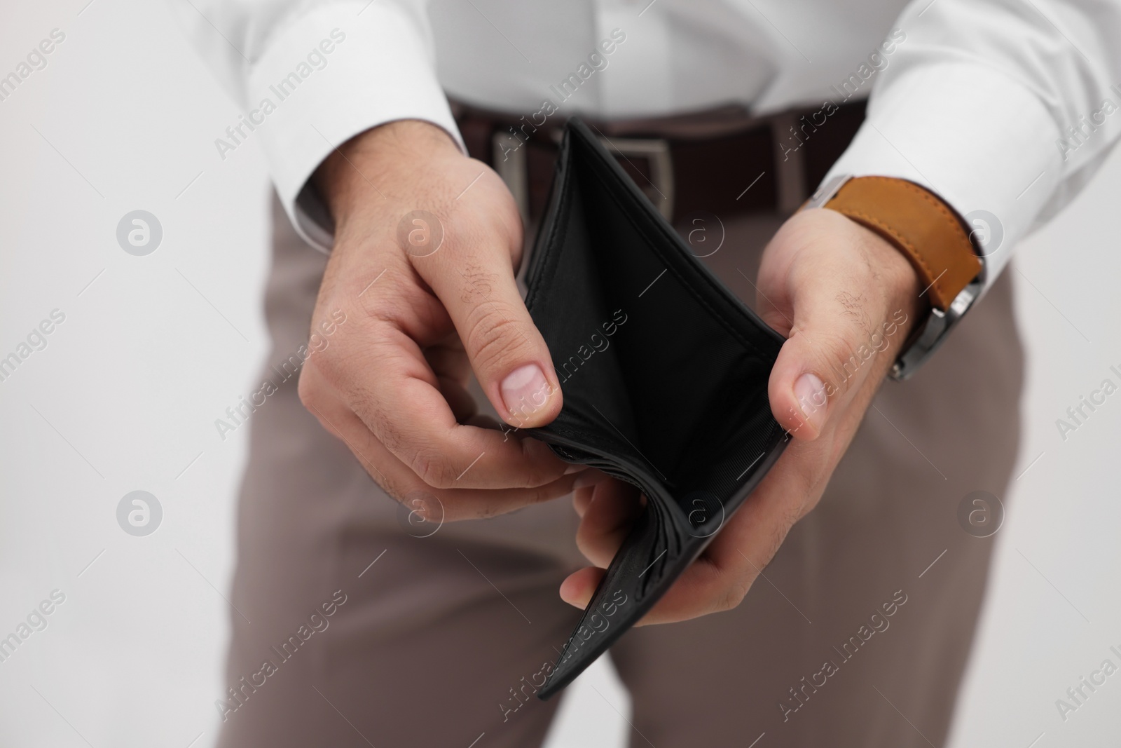 Photo of Man with empty wallet against light background, closeup