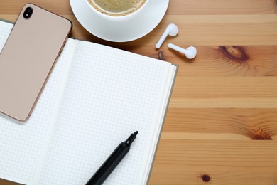 Photo of Empty notebook, coffee, smartphone and stationery on wooden table, flat lay. Space for text