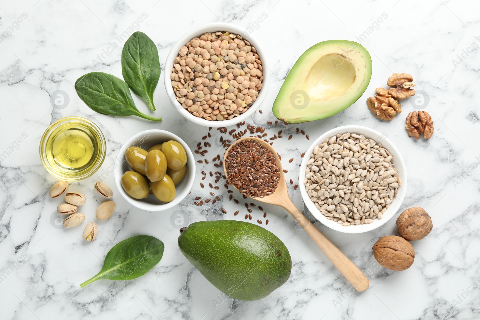 Photo of Different products and seeds high in healthy fats on white marble table, flat lay