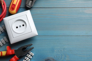 Set of electrician's tools and accessories on light blue wooden table, flat lay. Space for text