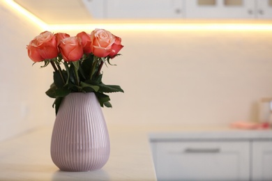 Photo of Vase with beautiful roses on countertop in kitchen, space for text. Interior design