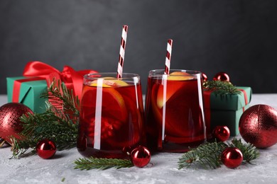Photo of Delicious Sangria drink in glasses and Christmas decorations on grey textured table, closeup