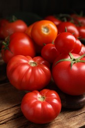Photo of Many different ripe tomatoes on wooden table, closeup