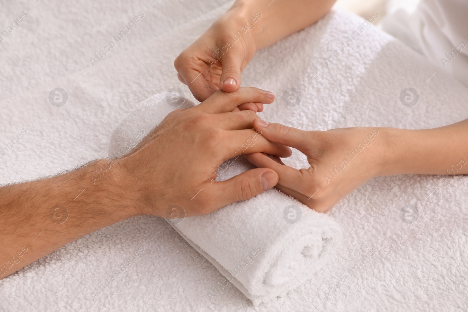 Photo of Man receiving hand massage on soft towel, closeup