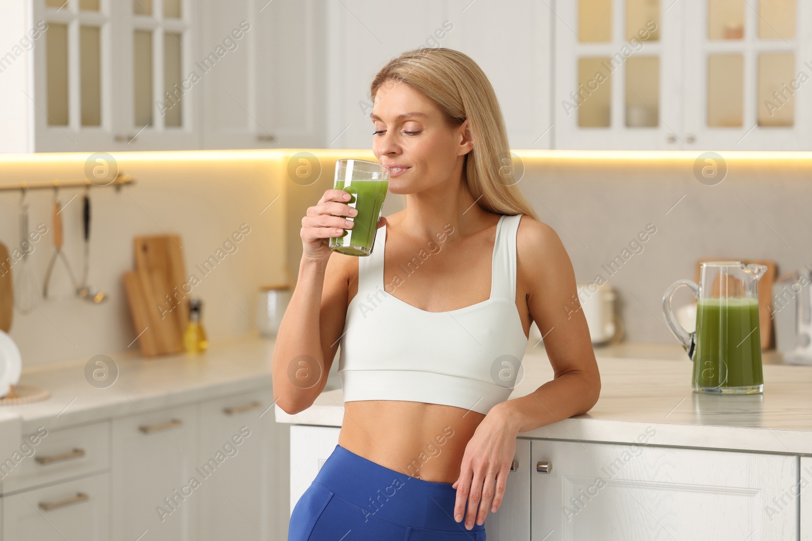 Photo of Woman drinking fresh celery juice in kitchen