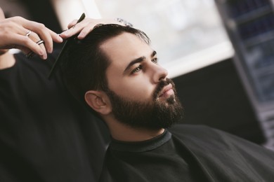 Image of Professional hairdresser working with bearded client in barbershop