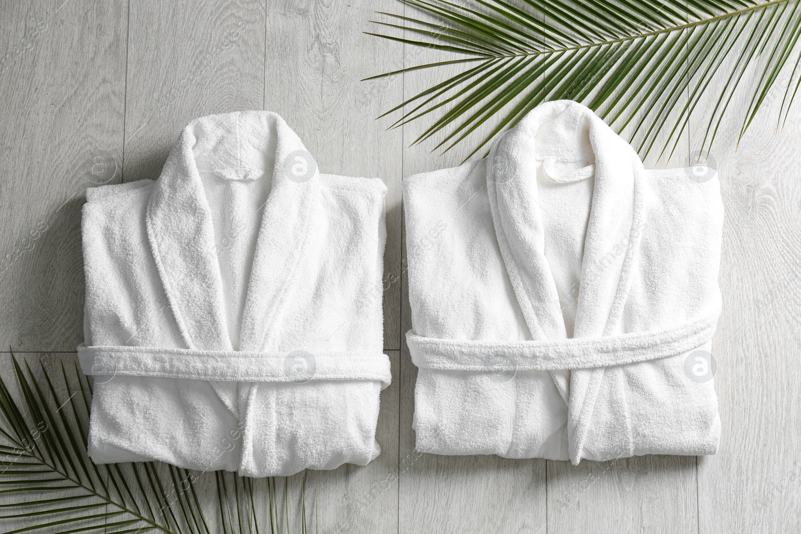 Photo of Flat lay composition with clean folded bathrobes on light wooden background