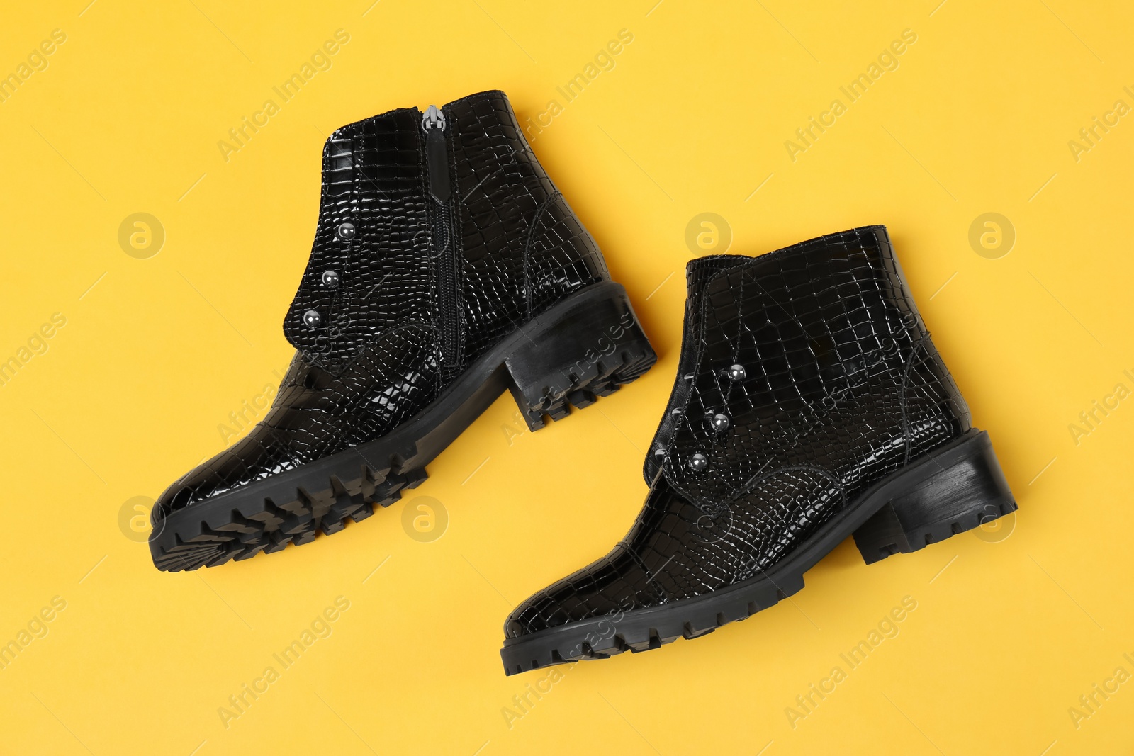 Photo of Pair of stylish ankle boots on yellow background, top view